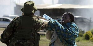 A police officer roughs up a woman during a memorial rally at Jacaranda grounds in Nairobi.