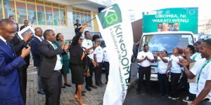 Kingdom Bank Board Chair Margaret Karangatha accompanied by bank staff flags off a market activation roadshow during the grand opening of the banks 20th branch in Gikomba.