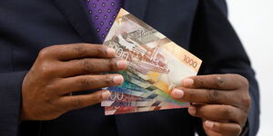 A person holding Kenya shilling notes